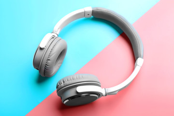 Wireless white and grey headphones on pink-blue background