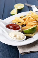 French fried potatoes with sauce and lime on white tray