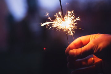 Man holding bright festive Christmas sparkler in hand, tinted ph