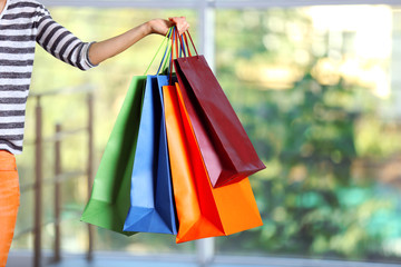 Female hand holding shopping bags on defocused background