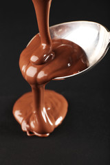 Chocolate poured on a spoon on dark background