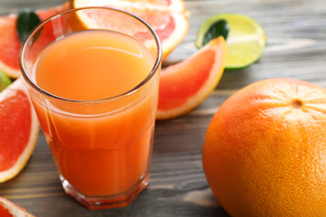 Glass of grapefruit juice and fresh fruits on wooden background