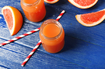 Grapefruit juice in bottles and fresh fruits on dark blue wooden background