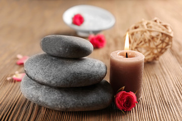 Fototapeta na wymiar Beautiful composition of aroma candle with pebbles and flower on wooden background