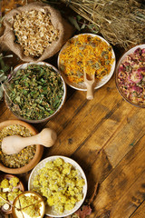 Assortment of dry medicinal herbs in bowls on wooden background top view