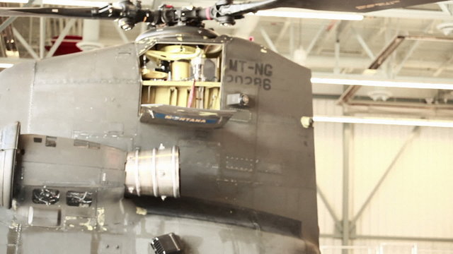Shot showing the tail end of a CH-47 Chinook Helicopter leaving a hangar.