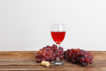 Wine and grape on wooden table against light background