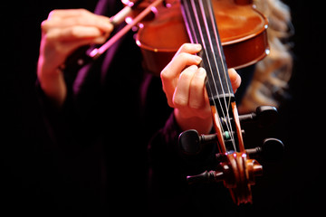 Woman plays violin on black background, close up