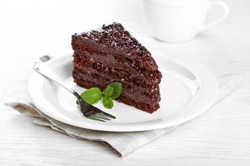 Chocolate cake with chocolate cream on plate, on light background