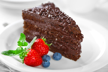 Chocolate cake with chocolate cream and fresh berries on plate, on light background