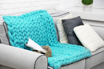 Knitted woolen blanket on sofa, on home interior background