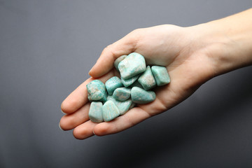 Woman holding semiprecious stones in her hand on dark grey background