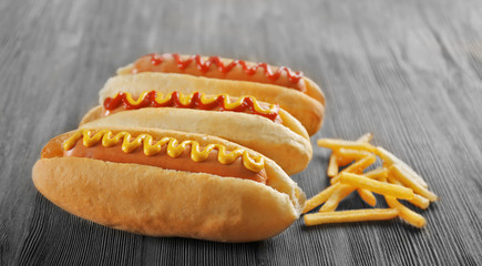 Tasty hot-dogs with French fries on wooden background