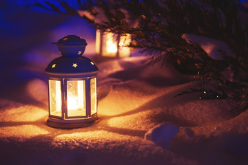 Two Lantern with burning candle on snow in the evening. Tinted p - obrazy, fototapety, plakaty