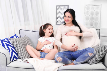 Pregnant mother and daughter in the room