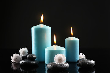 Spa composition of blue candles, flowers and stones on black background