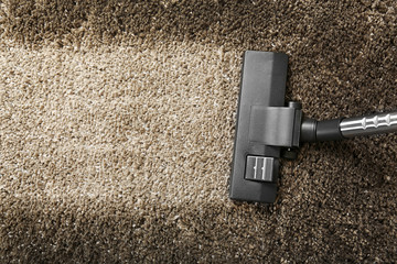 Cleaning concept - vacuum cleaner on grey soft carpet, close up