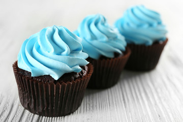 Delicious cupcakes on white wooden background, close up