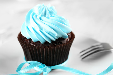 Delicious chocolate cupcake with blue cream on decorated wooden  table, close up