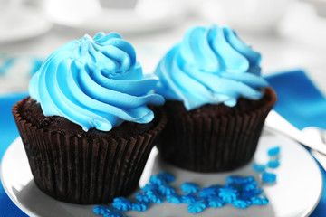 Delicious chocolate cupcakes with blue cream on decorated wooden  table, close up