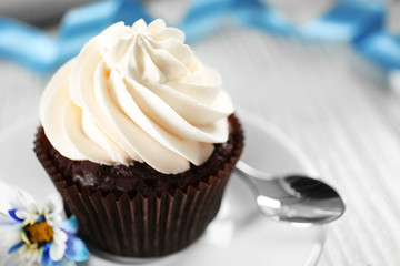 Delicious chocolate cupcake with cream on decorated wooden  table, close up