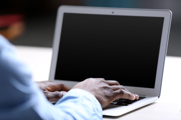 African American businessman in blue shirt working on laptop, close up