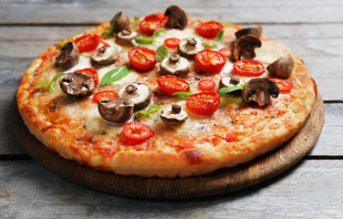 Tasty fresh pizza decorated with mushrooms and tomatoes on wooden background, close up