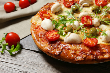Delicious pizza, fresh vegetables and cotton napkin on wooden background, close up