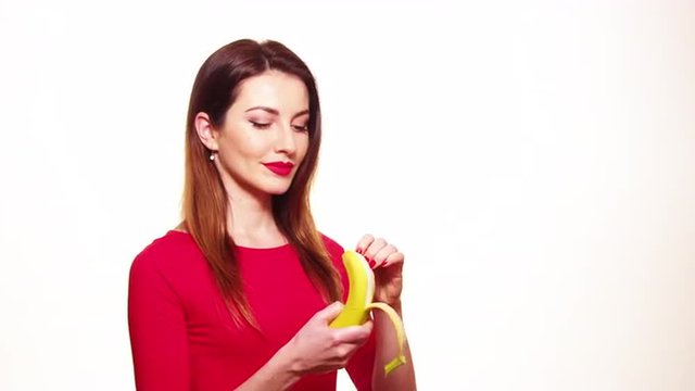 Sexy Woman in Red Clothes Eating Banana on White Background Isolated