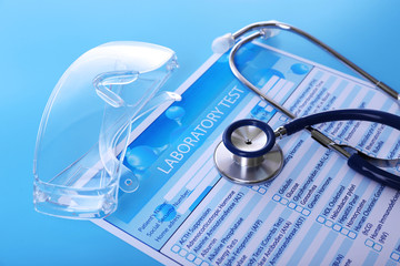 Laboratory test list, stethoscope and eyeglasses on blue background, close up