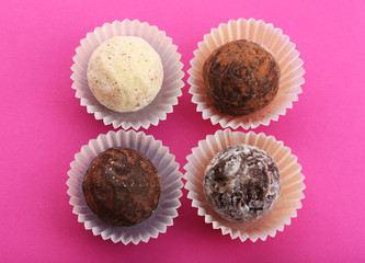 Group of chocolate truffles in paper cups, on pink background