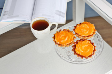 Sweet cakes with tangerines on table, close upbook