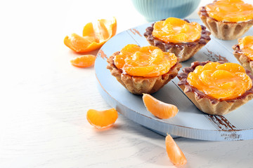 Sweet cakes with tangerines on table, close up