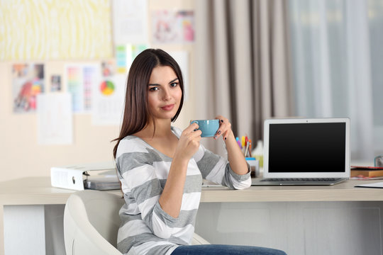 A beautiful young woman with a cup of tea working at home as a freelancer