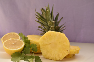 Pineapple slices. lemon and parsley on white table
