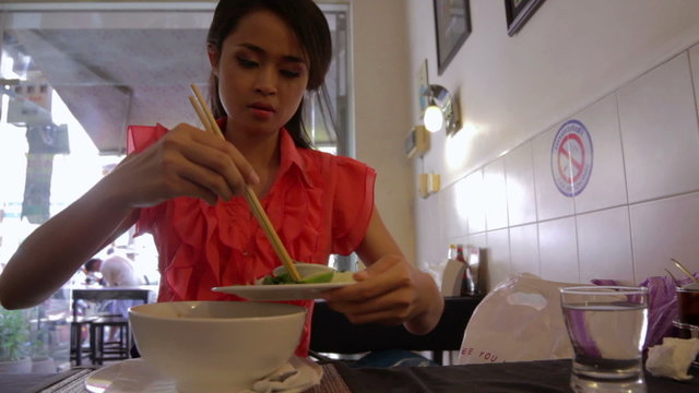 Asian girl eating noodle in a local restaurant, phnom penh