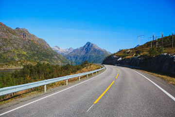 Picturesque Norway road landscape on high mountains, lake and fjord with blue sky in summer day, Norge.