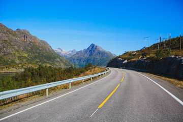 Picturesque Norway road landscape on high mountains, lake and fjord with blue sky in summer day, Norge.