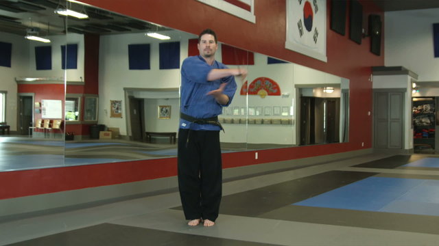 Man in a karate studio practicing bow staff weapon moves