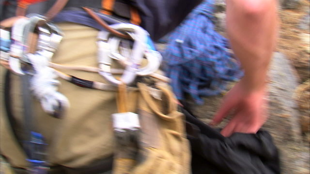 Mountain climber packing his pack with gear.