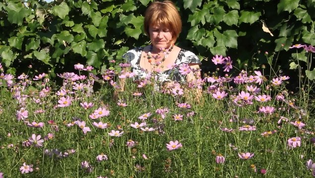 Woman with flowers grown.
Woman admires grown flowers.