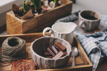 cozy winter or spring morning at home. Coffee, milk and chocolate on wooden tray. Hyacinth flowers on background. Warm mood.