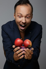 Smiling man looking at apples in his arms.