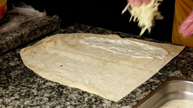 Making a shawarma or doner kebab with chicken meat and vegetables, wrapping in flat bread