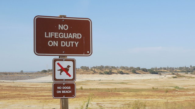 Zoom out of No Lifeguard On Duty sign, revealing dry portion of Folsom Lake in October 2015.