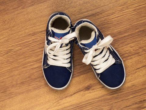 Pair of blue children's sneakers on the wooden floor