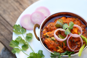 Butter chicken mutton curry or Indian style cottage cheese curry in a brass bowl with Salads.