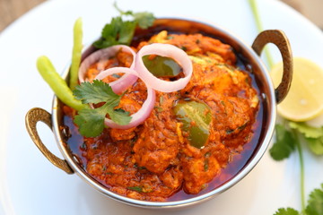Butter chicken mutton curry or Indian style cottage cheese curry in a brass bowl with Salads.