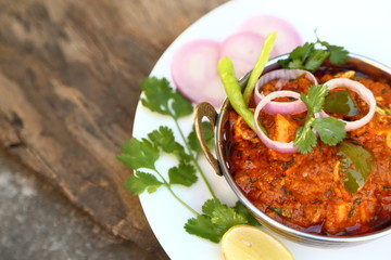 Butter chicken mutton curry or Indian style cottage cheese curry in a brass bowl with Salads.