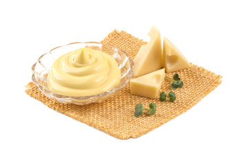 Transparent bowl with cheese sauce should lie on sacking near triangles of cheese with holes